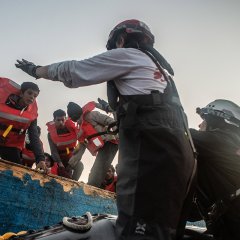 Menschen auf einem Holzboot, das zu sinken droht, werden von unseren Teams am 11. Mai 2022 im zentralen Mittelmeer gerettet.