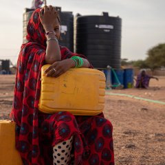 Une femme assise devant un site de distribution d'eau, dans un camp de déplacés à Djibo. Burkina Faso. 18 octobre 2020