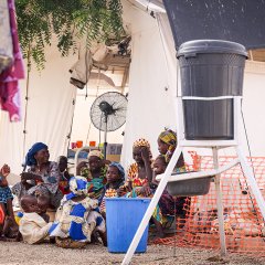Eine Gruppe von Frauen teilt sich den Platz vor dem therapeutischen Ernährungszentrum, in dem ihre Kinder behandelt werden. Katsina, Nigeria, 24. Mai 2023.
