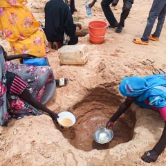 Geflüchtete aus dem Sudan versuchen, Wasser aus dem Wadi in der Nähe des Camps Ourang zu schöpfen, da die Wasserversorgung in den Camps knapp ist. Tschad, August 2023.