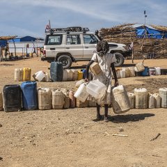 Eine Frau trägt mehrere Wasserkanister im Camp Metché im Osten des Tschad. November 2023. 