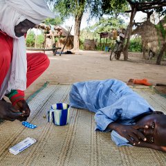 Un garçon souffre de la malaria. Son père prépare le traitement contre la fièvre. Tchad, Bongor, octobre 2007.