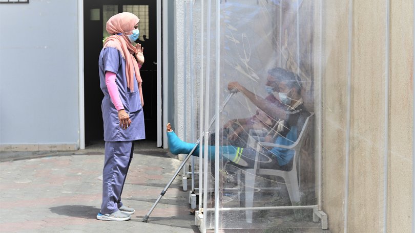 Rania Sammour, conseillère en santé mentale pour MSF, discute avec un patient de 23 ans, blessé lors d'une frappe aérienne à Gaza en mai 2021, alors qu'il attend un examen médical.