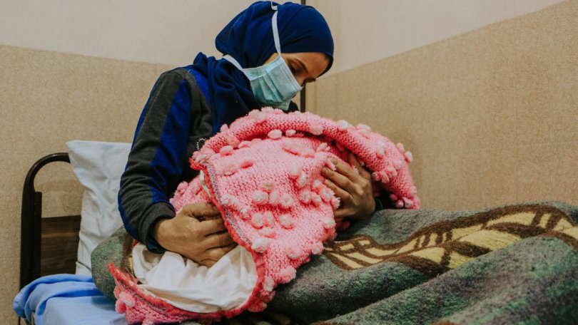 Une femme déplacée tient son nouveau-né dans ses bras