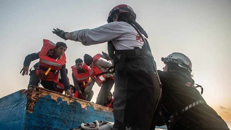 Menschen auf einem Holzboot, das zu sinken droht, werden von unseren Teams am 11. Mai 2022 im zentralen Mittelmeer gerettet.