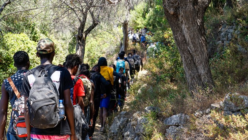 Des personnes nouvellement arrivées marchent sur un chemin rocheux sur l'île de Samos, en Grèce.