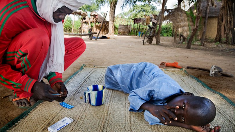 Un garçon souffre de la malaria. Son père prépare le traitement contre la fièvre. Tchad, Bongor, octobre 2007.