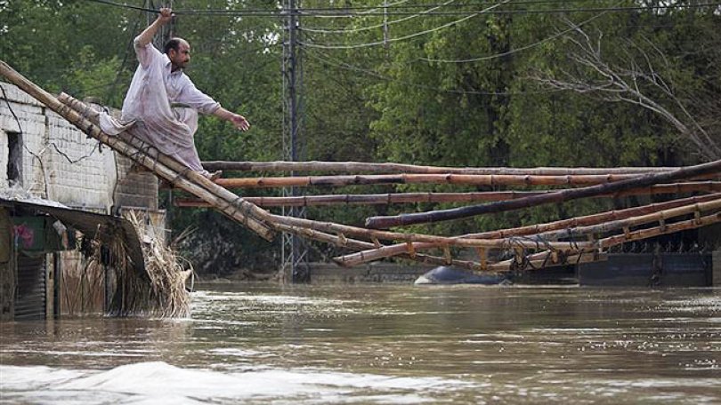 Un homme tente de quitter sa maison inondée en traversant un pont de fortune à Nowshera, au Pakistan dans la province du nord-ouest de Khyber Pakhtunkhwa. 31/07/2010