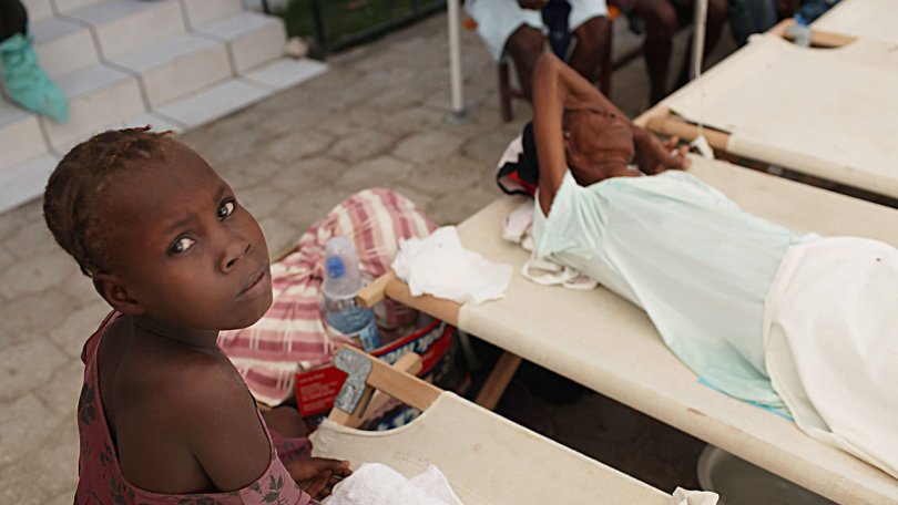 Une fille veille sur un membre de sa famille atteint des symptômes du choléra dans un hôpital de Saint-Marc dirigé par le gouvernement haïtien où MSF traite les patients de l’épidémie de choléra, Haïti, 27.10.2010