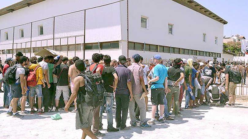Les migrants font la file à l'extérieur du stade de Kos en attendant d'être enregistrés par la police grecque.