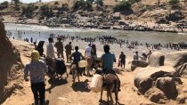 Une quarantaine de personne se prépare à traverser le fleuve, chargé de sacs et de bidons.