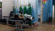 Un patient allongé sur un fauteuil au milieu d’un couloir. Derrière lui, des bonbonnes d’oxygène.