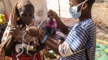 Le personnel de MSF aide une femme réfugiée à mettre son masque à l'intérieur de la clinique gérée par MSF dans le camp de réfugiés d'Um Rakuba, Sudan