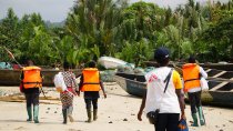 Une équipe MSF marche sur le sable pour atteindre le village d'Enyenge où ils mènent le deuxième jour de la campagne de vaccination contre le choléra. Enyenge, Sud-Ouest du Cameroun, 17 février 2022