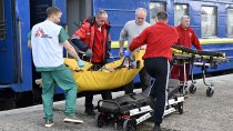 Des ambulanciers et des médecins MSF transfèrent un patient du train médicalisé à une ambulance. Lviv, Ukraine, 10 avril 2022.