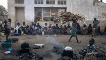 Un enfant déplacé marche avec des tiges de mais sur la tête près des tribunes du stade de Rugabo